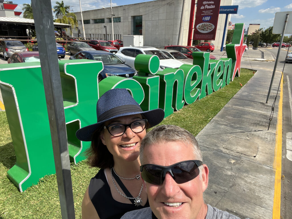Image of a woman and man standing in front of a large lettered Heineken sign