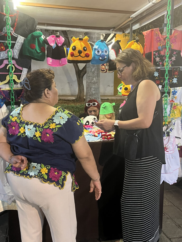two women look at knitted items in market in Merida Mexico