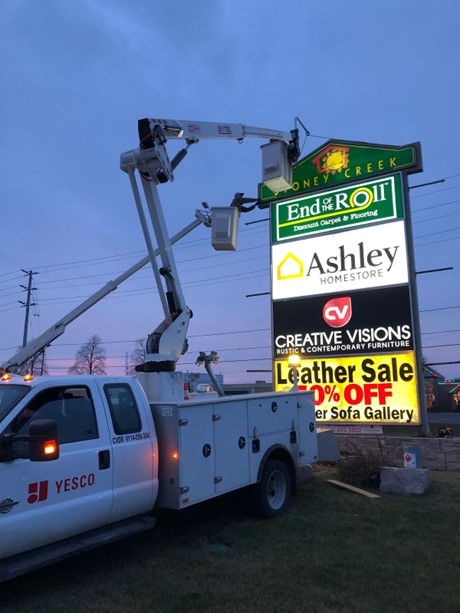 A yesco truck servicing a business sign