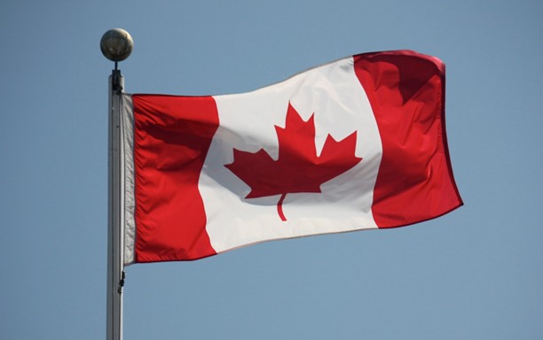 A photo f a Canadian flag on a flagpole blowing in the wind